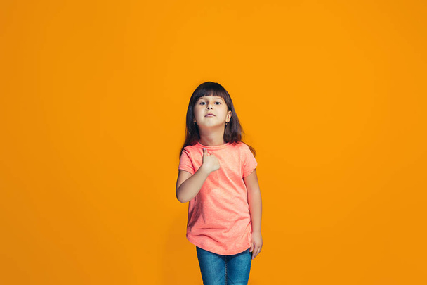 The happy teen girl standing and smiling against orange background. - Foto, Imagen