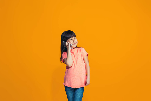 Счастливая девушка-подросток, стоящая и улыбающаяся на оранжевом фоне
. - Фото, изображение