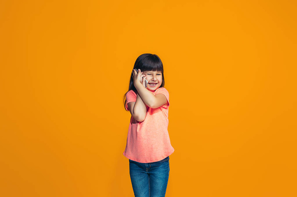 The happy teen girl standing and smiling against orange background. - Фото, зображення