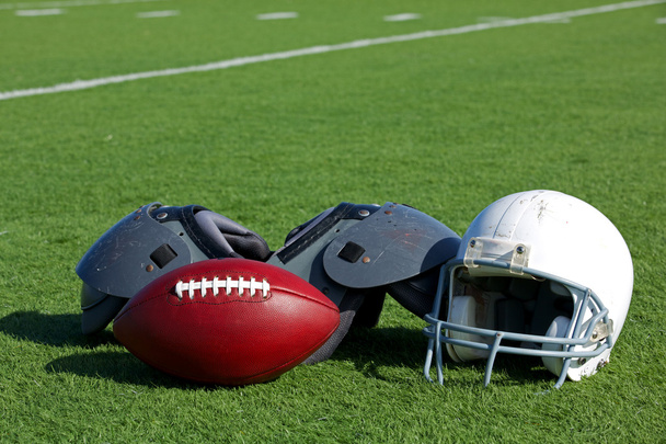Fútbol americano y casco en el campo
 - Foto, Imagen
