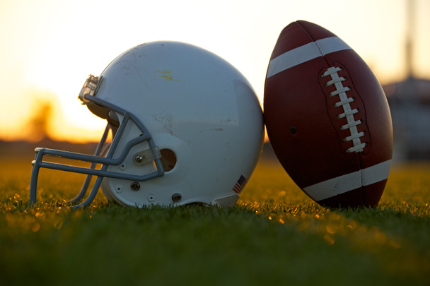 Futebol e capacete no campo ao pôr do sol
 - Foto, Imagem