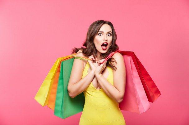 young woman with colorful shopping bags posing against pink background, shopping and discount concept - Photo, Image
