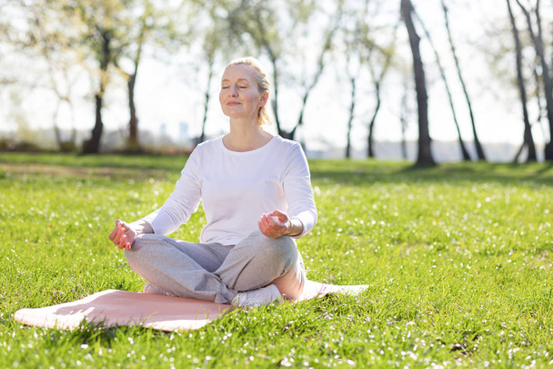 Nice aged woman meditating - Фото, изображение