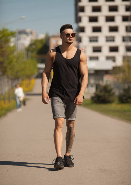 Handsome muscular man with tattoo posing in European city - Photo, image