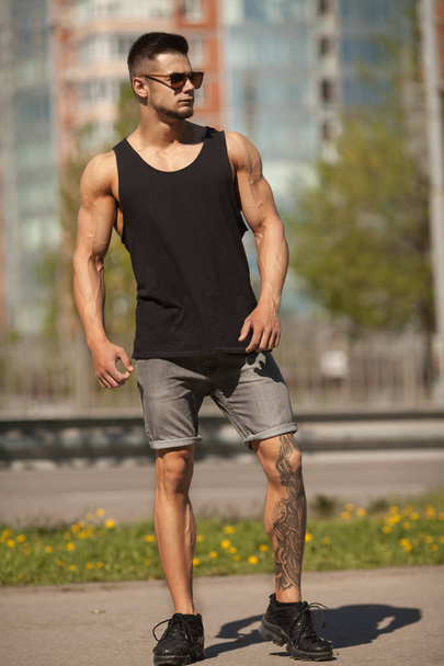 Handsome muscular man with tattoo posing in European city - Foto, afbeelding