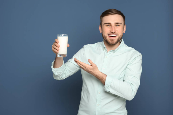 Young man with glass of tasty milk on color background - Foto, imagen