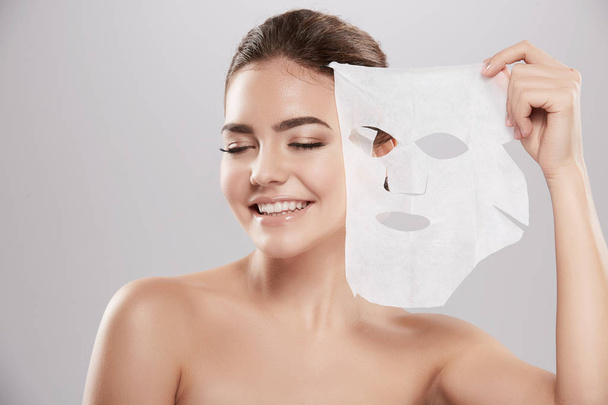 красивая и естественная молодая женщина наносит маску для лица, концепция ухода за кожей, лечение кожи, увлажняющая маска кожи
 - Фото, изображение