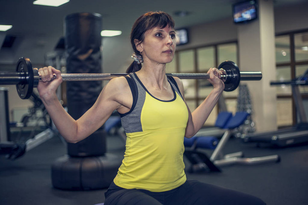 ασκήσεις φυσικής κατάστασης, μια γυναίκα εκτελεί μια άσκηση μπαρ πάγκο τύπου στους ώμους - Φωτογραφία, εικόνα