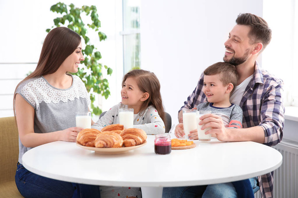 Happy family having breakfast with milk at table - Фото, изображение