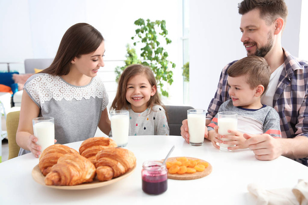 Счастливая семья завтракает молоком за столом
 - Фото, изображение