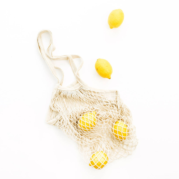 Limões crus frescos em saco de cordas no fundo branco. Flat lay, conceito de verão vista superior
. - Foto, Imagem