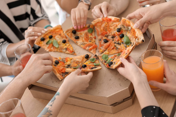 Молодые люди едят вкусную пиццу за столом, крупным планом
 - Фото, изображение