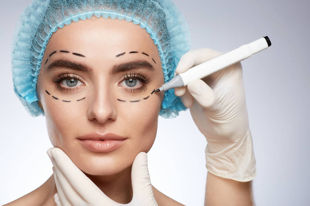портрет привлекательной женщины, концепция пластической хирургии. Модель с проколами на лице, руки в перчатках
 - Фото, изображение