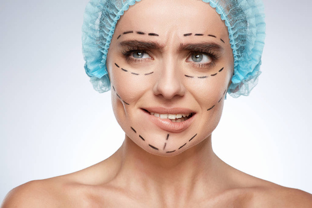 kauneusmuotokuva pelästynyt nainen, plastiikkakirurgia käsite. Malli sinisessä korkissa, jossa on reiät kasvoissa
 - Valokuva, kuva