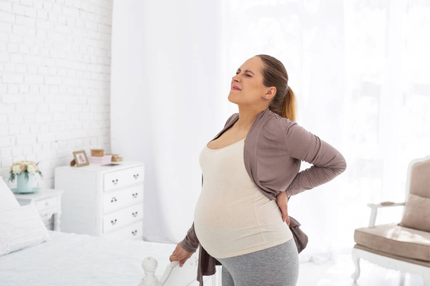 Dismal pregnant woman relieving back pain - Фото, изображение