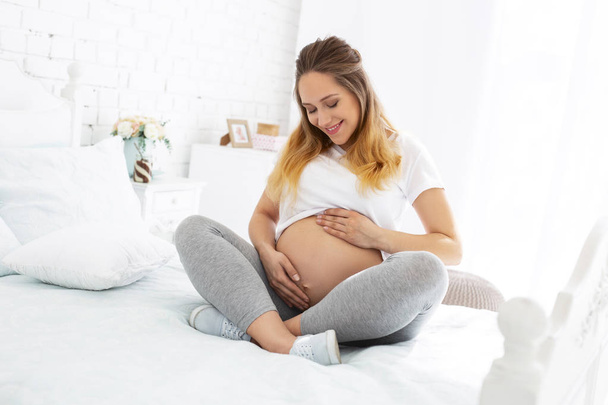 Happy pregnant woman admiring belly - Photo, Image