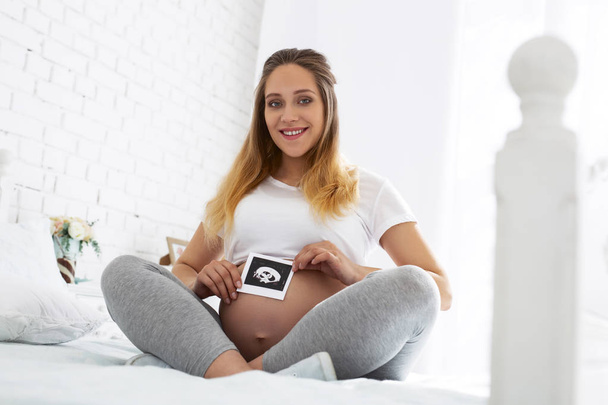 Jolly pregnant woman showing ultrasound - Zdjęcie, obraz