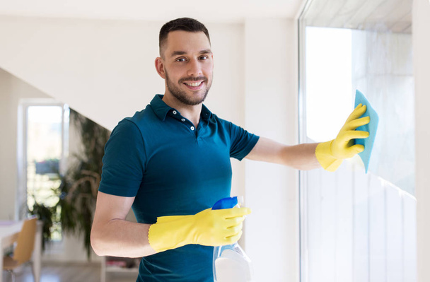 man in rubber gloves cleaning window with rag - Fotografie, Obrázek