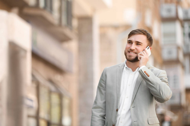 Portrait of young businessman talking on phone outdoors - Fotó, kép