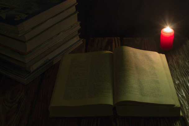 candle and a book of the Bible on wooden background at night. - Foto, imagen