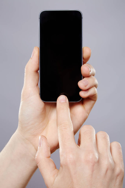 male hands using mobile phone over grey background  - Photo, image