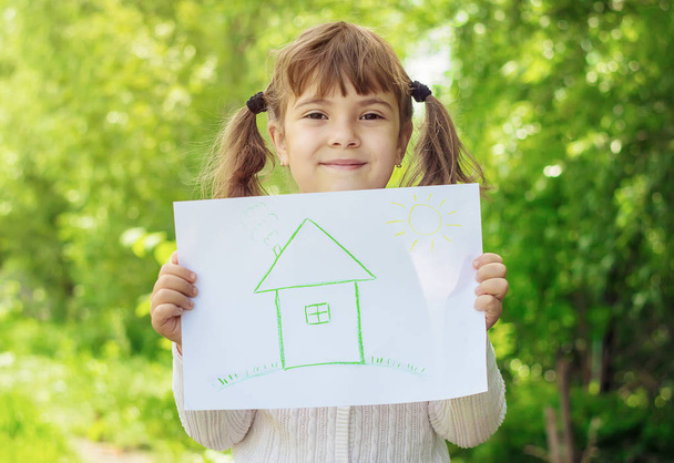 Σχέδιο του ένα πράσινο σπίτι στα χέρια ενός παιδιού. Επιλεκτική εστίαση.  - Φωτογραφία, εικόνα