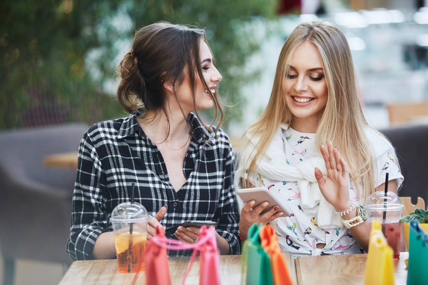 attractive young women with colorful shopping bags using mobile phones in cafe - Foto, Imagem