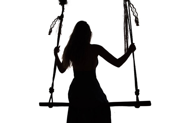 Sillhouette of a woman sitting on a seesaw - Фото, изображение