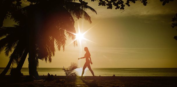 Flexible woman training on a tropical beach - Photo, Image