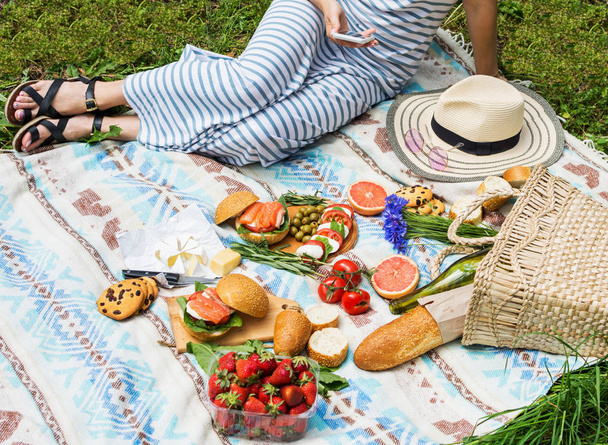 Пикник с корзиной, бутербродами, фруктами, клубникой, салатом и оливками
. - Фото, изображение