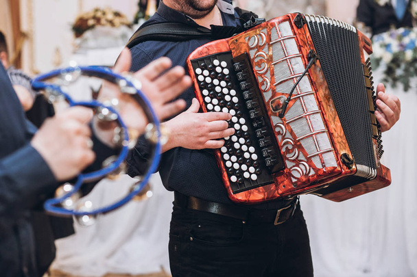 musiciens jouant sur accordéon et tambourin, orchestre musical se produisant à la réception de mariage. temps amusant à la fête
 - Photo, image