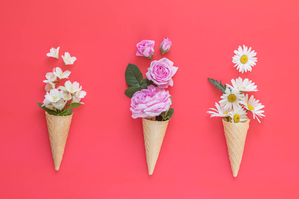 Waffle cone with pink roses, chamomiles and jasmine flowers bouquet on pink background. Flat lay, top view floral background. - Photo, Image