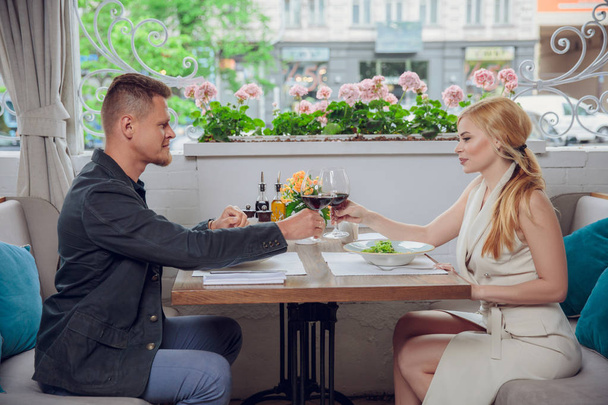 Mooie jonge paar met glazen rode wijn in luxe restaurant - Foto, afbeelding