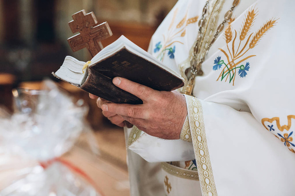 司祭持株聖書。結婚式結婚を教会で祈り、男の手の中の神聖な本。伝統的な宗教的な結婚式 - 写真・画像