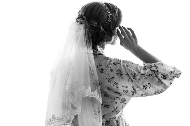 Прекрасная счастливая невеста позирует у окна, стоя в шелковом халате. счастливые моменты. концепция брака. Невеста готовится утром. пространство для текста. черный и белый
 - Фото, изображение