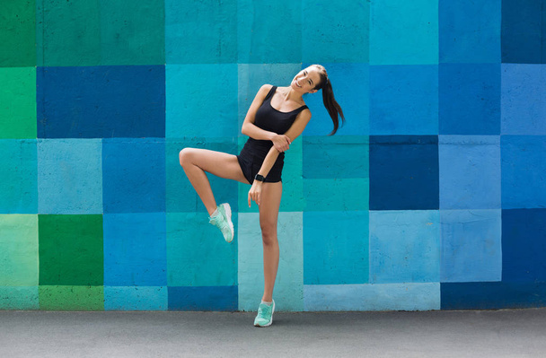Gyönyörű fitness lány pózol a kék háttér - Fotó, kép