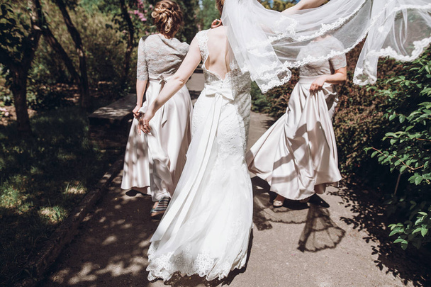счастливая невеста с подружками невесты веселятся в зеленом парке
 - Фото, изображение