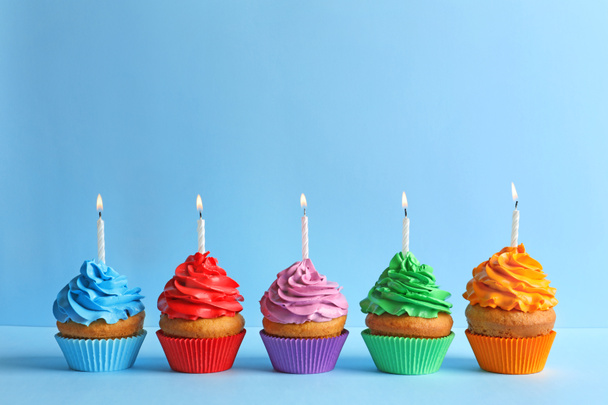 Deliciosos cupcakes de cumpleaños con velas sobre fondo de color
 - Foto, imagen
