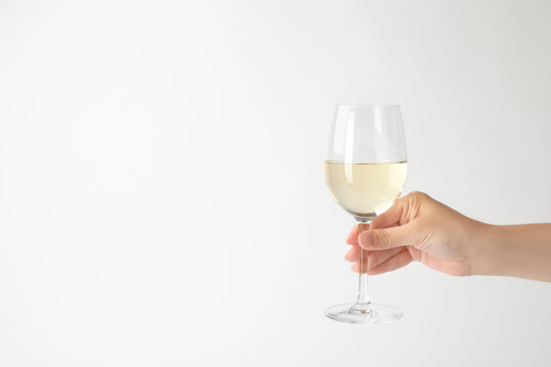 Woman holding glass of expensive white wine on light background - Valokuva, kuva