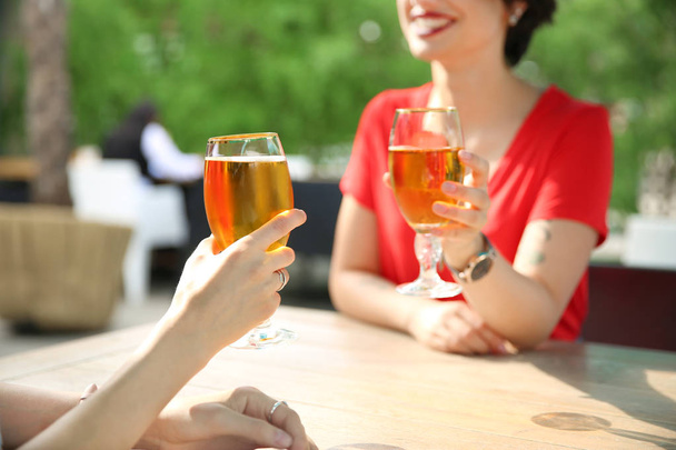 Young women with glasses of cold beer at table - Fotoğraf, Görsel