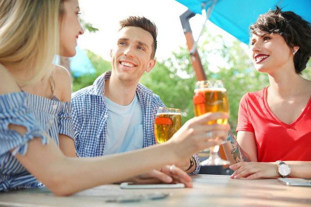 Young people with glasses of cold beer at table - Foto, immagini