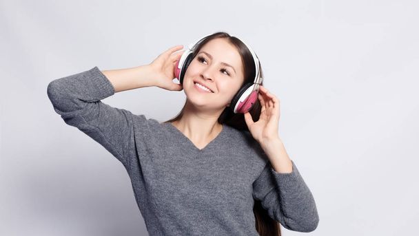 People, leisure and technology concept - happy woman or teenage girl in headphones listening to music from smartphone and dancing - Foto, imagen