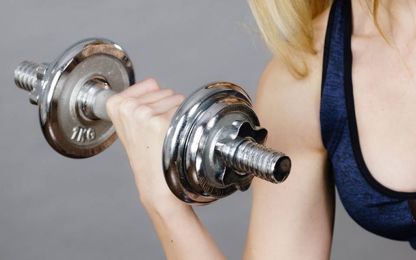 Strong woman lifting dumbbells weights. Fit girl attractive blonde model exercising gaining building muscles. Fitness and bodybuilding. - Zdjęcie, obraz