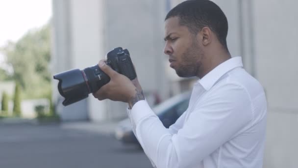 アフリカ系アメリカ人写真家は、彼のカメラ街背景で屋外で写真を取る - 映像、動画