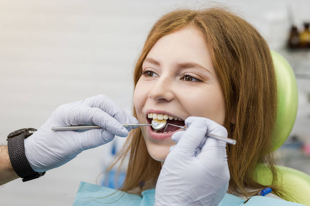 Dentist examining girl's teeth in clinic. Dental problem. Healthy Smile. - Фото, изображение