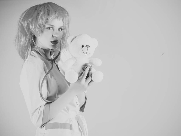Girl examining teddy bear toy with stethoscope - Фото, изображение