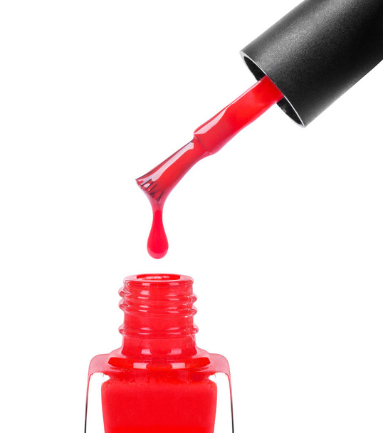 Red nail polish dripping from brush into bottle closeup, isolated on white background - Fotografie, Obrázek