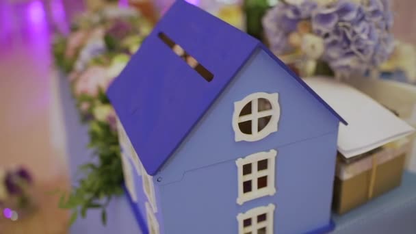 Spielzeughaus auf dem Tisch mit frischen Blumen - Filmmaterial, Video