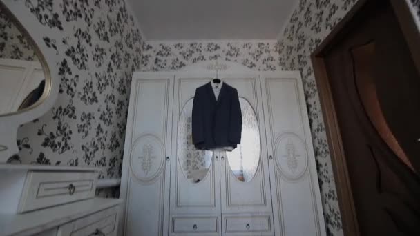 A mans jacket hangs on a hanger in the room - Footage, Video
