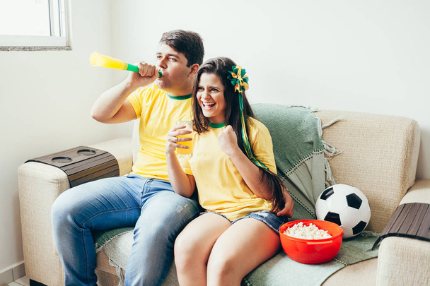 Couple watching soccer game on television, celebrating goal and screaming - Foto, afbeelding